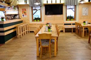 a restaurant with wooden tables and chairs and a flat screen tv at Balónový hotel a pivovar Radešín in Radešín