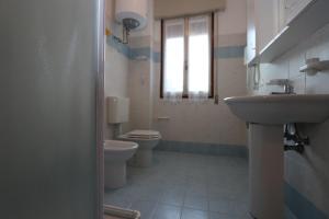 bagno con lavandino, servizi igienici e finestra di Villa Stefano a Bibione