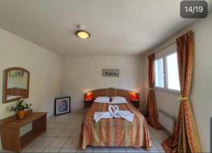 a bedroom with a bed with a bow on it at Hotel des Gorges au Viaduc in Rivière-sur-Tarn