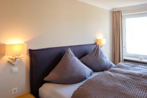 een slaapkamer met een bed met kussens en een raam bij Sola Bona 24 in Westerland +9 foto's