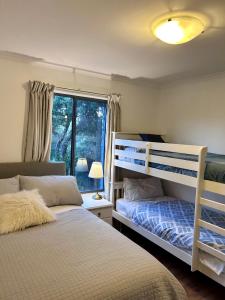 a bedroom with two bunk beds and a window at Magic Beach Cottage in Venus Bay