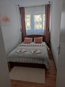 Un dormitorio con una cama con almohadas rosas y una ventana en Apartman Emy, en Karlovac