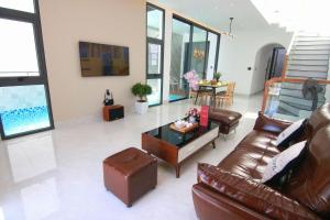 ein Wohnzimmer mit einem Ledersofa und einem Tisch in der Unterkunft Sea Villa Bãi Dâu View Biển - Đi Bộ Ra Biển in Vũng Tàu