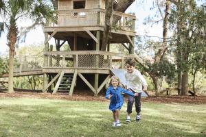 a boy and a girl running in front of a tree house at Montage Palmetto Bluff in Bluffton