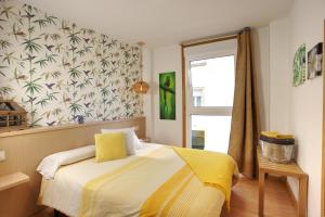 a bedroom with a bed with yellow sheets and a window at VM Apartamentos Turísticos in Santiago de Compostela