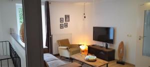 uma sala de estar com um sofá e uma televisão em Au Marronnier em Lontzen