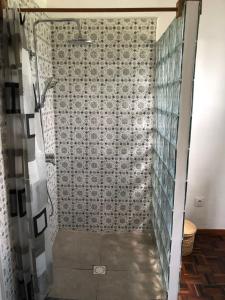 y baño con ducha y pared de azulejos. en Maison madasgascar, en Ampasikely