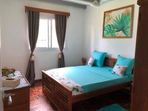 1 dormitorio con cama con sábanas azules y ventana en Maison madasgascar, en Ampasikely