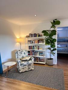 a living room with a chair and a book shelf at Magic Beach Cottage in Venus Bay