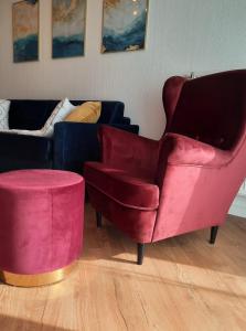 salon z czerwonym krzesłem i kanapą w obiekcie Apartament Pełen Słońca - Pinea Pobierowo w Pobierowie