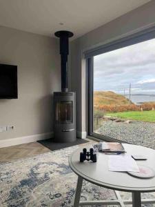 a living room with a fireplace and a table and a window at Mary’s Seaview Clifden in Galway