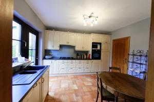 een keuken met witte kasten en een houten tafel bij La colline aux hirondelles in La-Roche-en-Ardenne