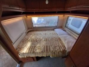 a bed in the back of a van with two windows at Caravan near the sea 6 in Ugljan
