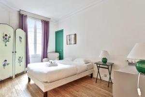 biała sypialnia z łóżkiem i oknem w obiekcie Appartement Caulain - Welkeys w Paryżu