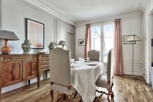 uma sala de jantar branca com uma mesa e cadeiras em Exceptional flat at the heart of Montmartre - Paris - Welkeys em Paris