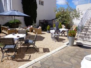 een terras met tafels, stoelen en een parasol bij Casa Cosy Le Pouliguen in Le Pouliguen