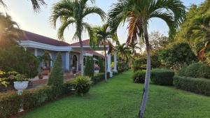 uma casa com palmeiras num quintal em Beautiful bungalow with a communal outdoor pool and 2 km from the sandy beach em Ban Sa