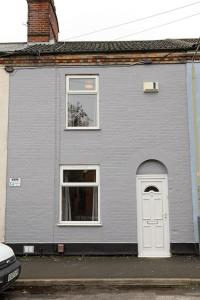 une maison grise avec une porte et des fenêtres blanches dans l'établissement Cowgate Rest, à Norwich