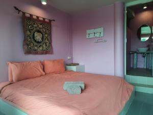 a pink bedroom with a bed with a towel on it at Pingplalee Resort in Sai Yok