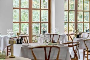 a dining room with white tables and chairs and windows at Gl Skovridergaard in Silkeborg