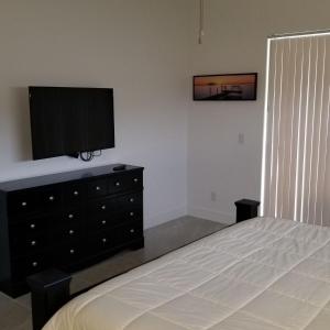 - une chambre avec un lit et une télévision sur une commode dans l'établissement Stunning New Home in Cape Coral Florida, à Cape Coral