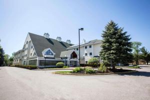 a large white building with a tree in a driveway at Comfort Inn Concord South End in Concord