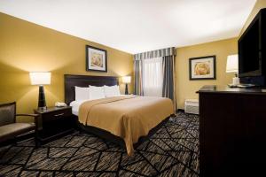 リバプールにあるQuality Inn and Suites Fairgrounds - Syracuseのベッドとテレビが備わるホテルルームです。