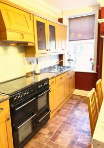 a kitchen with wooden cabinets and a black oven at The Georgian Apartment in Gosport