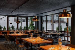un restaurante con mesas y sillas de madera y ventanas en Radisson Blu Hotel Espoo, en Espoo