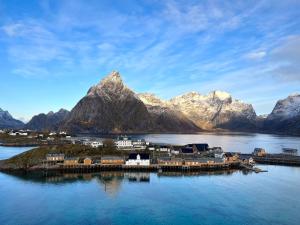 a small island in a body of water with mountains at Little White House in Reine
