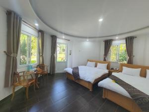 a room with two beds and a table and windows at LẠC DƯƠNG TIÊN CẢNH (BULGALOW) in Xuan An