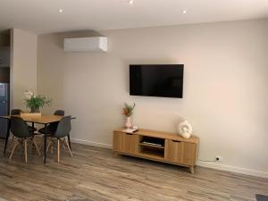 a living room with a table and a television on a wall at Shepparton Lakeside Serviced Apartment in Shepparton