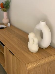 two white vases sitting on top of a wooden cabinet at Shepparton Lakeside Serviced Apartment in Shepparton