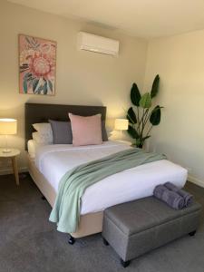 a bedroom with a large bed and a plant at Shepparton Lakeside Serviced Apartment in Shepparton