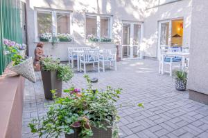 a patio with white tables and chairs and plants at Dom Pracy Twórczej Polska Akademia Nauk in Jurata