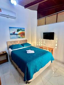 a bedroom with a blue bed and a television at Pousada HOME BEACH MAR porto das dunas BEACH PARK in Aquiraz