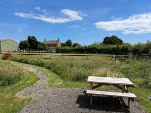 a wooden bench sitting next to a dirt road at Manor Farm Stay in Sutton on Sea
