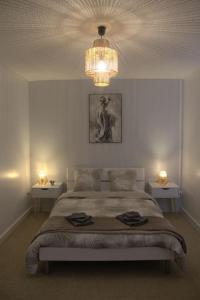 1 dormitorio con 1 cama grande y lámpara de araña en Gite de Tréguilly, en Pontchâteau