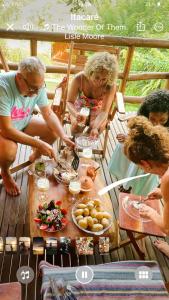 un grupo de personas sentadas alrededor de una mesa con comida en Vila Enayá, en Itacaré