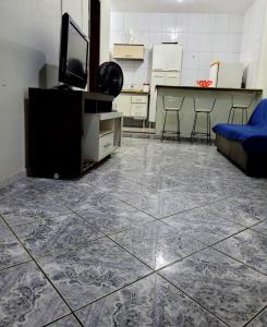 a living room with a tiled floor with a tv and chairs at Apartamento de 2 quartos in Piúma