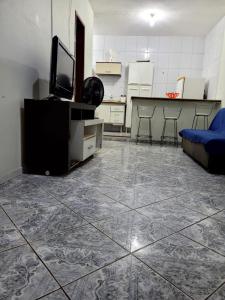 uma sala de estar com piso em azulejo, uma televisão e um sofá em Apartamento de 2 quartos em Piúma