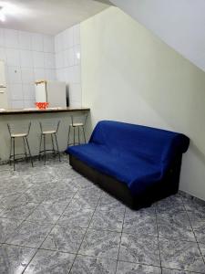 Cette chambre comprend un lit bleu et deux chaises. dans l'établissement Apartamento de 2 quartos, à Piúma