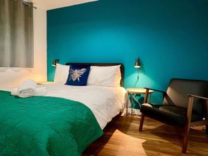 1 dormitorio con una pared azul, 1 cama y 1 silla en City SuperHost NQ & City Centre 1 BR with Parking, en Mánchester