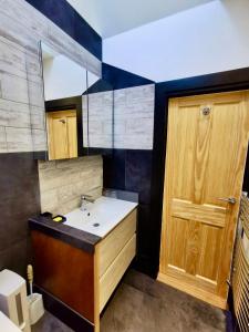 a bathroom with a sink and a wooden door at Seashells at 2 TRENCROM COURT ST IVES in Carbis Bay