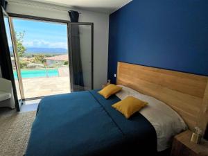 niebieska sypialnia z łóżkiem i dużym oknem w obiekcie Villa Terra Vecchia, 6 ou 12 personnes, vue imprenable, piscine chauffée w mieście Porto-Vecchio