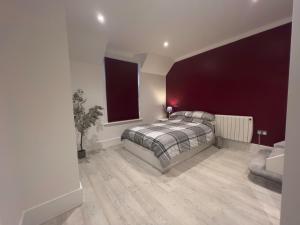 1 dormitorio con cama y pared roja en The Dragon Pad Boutique Apartment, en Royal Tunbridge Wells