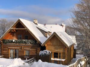 domek z bali i śniegiem na dachu w obiekcie Chaty Świerkowe Wzgórze - drewniane domy z sauną i balią w mieście Karpacz