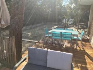 une terrasse en bois avec une table et des chaises bleues dans l'établissement Deux pièces ou studio Plage Sud à 200m, à Lacanau-Océan