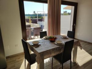 a dining room table with chairs and a large window at Holiday Home La Perla in Presicce