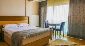 ディキリにあるPerla Hotelのベッド、テーブル、窓が備わる客室です。
